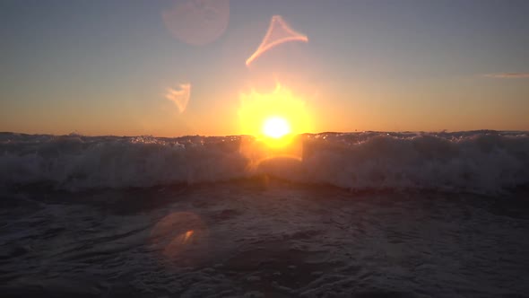 Waves break in the Pacific Ocean at sunset.