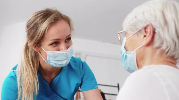 Masked Caucasian Caregiver Woman with Senior Pensioner Lady Talking Cheerfully