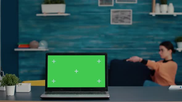 Modern Laptop with Green Screen Template on Desk at Home alt