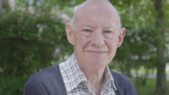 Portrait of Cute Smiling Old Man Sitting on a Bench in the Park