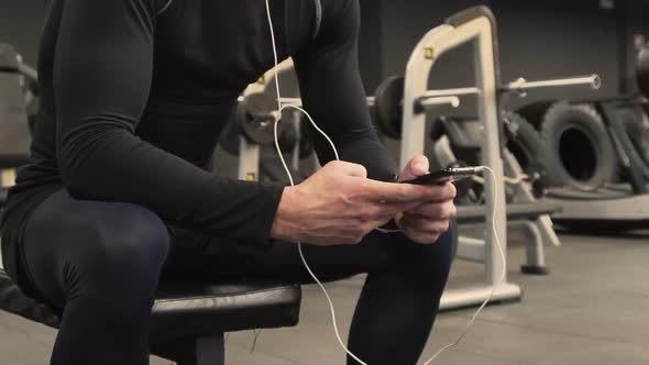 Medium Shot of Athletic Mans Hands Choosing Music on Cell Phone