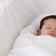 Baby girl sleeping in bassinet, with baby clothes beside - VideoHive Item for Sale