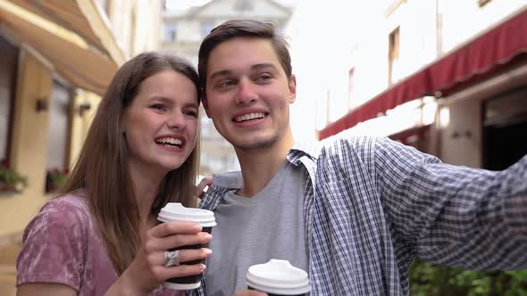 Couple Making Photo On Phone And Drinking Coffee At Street