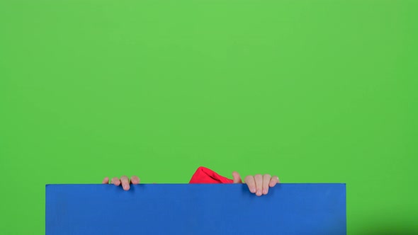 Child Boy Out of Hiding From Behind a Blue Poster on a Green Screen
