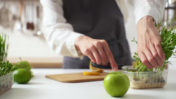 Cooking A Vegan Lunch. A Woman In An Apron Cuts Green Pea Sprouts. Healthy Eating From Food. Cooking