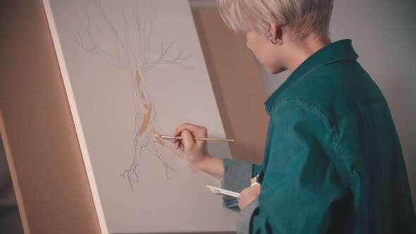 A Young Woman Artist Painting Tree Trunk in Beige Color in the Art Studio