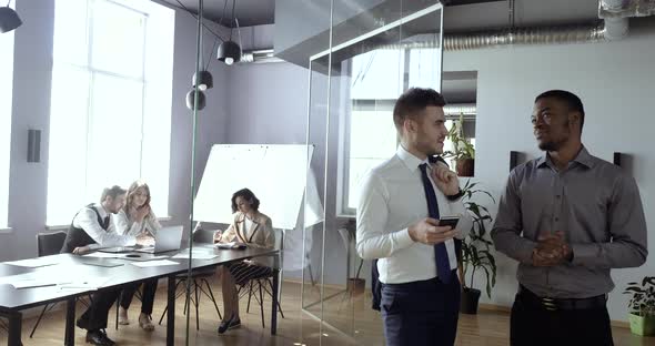 African American Guy New Employee of Company Foreigner Stands with Colleague White Man in Corridor