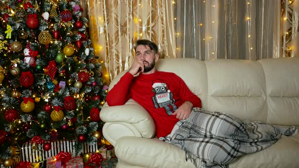 Young Caucasian Man Thinks Near to Christmas Tree