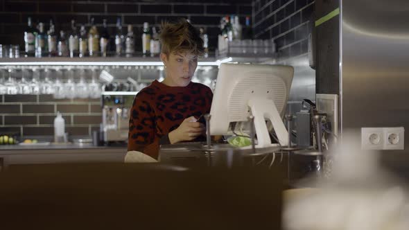 Shorthaired Woman Uses Computer and Phone at Restaurant Bar Slomo