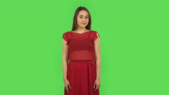 Tender Girl in Red Dress Is Smiling Broadly and Winking. Green Screen