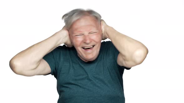 Portrait of Adult Frustrated Man 80s Having Gray Hair in Basic Tshirt Covering Ears and Screaming in