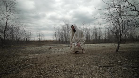 Religious Man Wearing Robe Kneeling and Praying