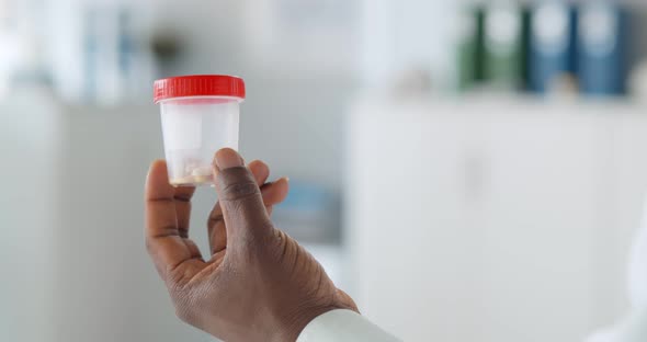 Close Up of Afroamerican Doctor Holding Plastic Bottle with Medication