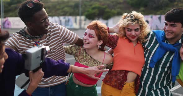 Young diverse people having fun with old vintage video camera outdoor