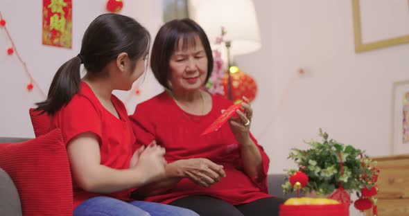 Happy Senior Asian Woman Giving Her Granddaughter A Lucky Red Envelope for Chinese New Year Gift.