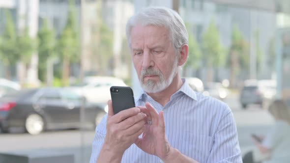 Old Man Browsing Internet on Smartphone Outdoor