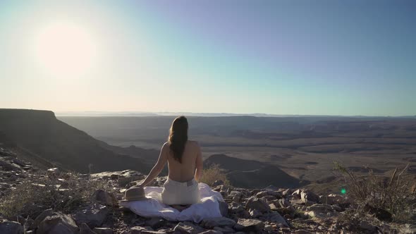 Young Woman Sitting Topless on Blanket at Edge of Fish River Canyon in Namibia