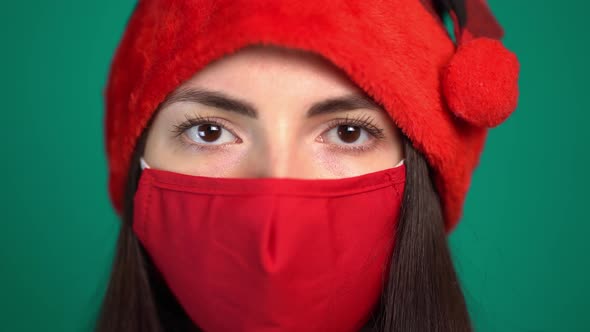 Portrait of Young Woman with Red Medical Face Mask and Santa Hat, Looking at Camera