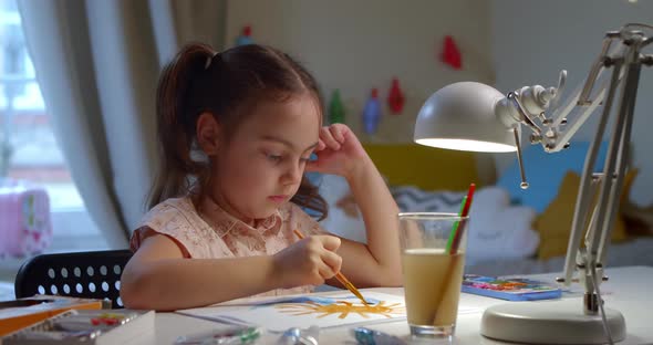 Preschool Girl Learns to Draw with Watercolor Paint Sitting at Home