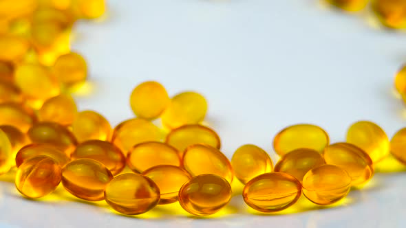 Fish Oil Capsules Rolling on a White Surface. Healthy Background and Medicine Concept