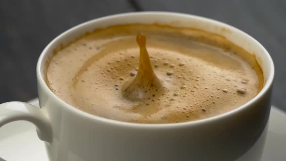 Splashes of Coffee in White Espresso Coffee Cup, Drops of Coffee Falls Into the Foam