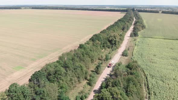 Farming tractor with sprayer driving on gravel countryside road