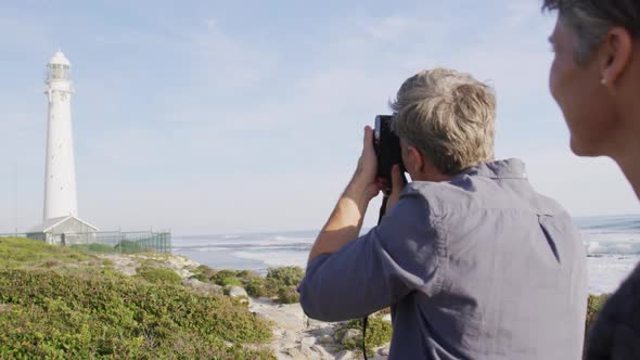 Caucasian couple enjoying free time by sea on sunny day taking photo with camera