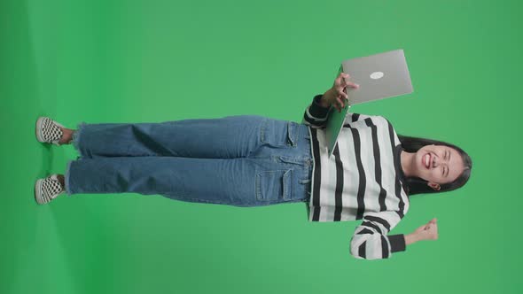 Full Body Of A Happy Asian Woman Celebrating While Using Computer On The Green Screen Background