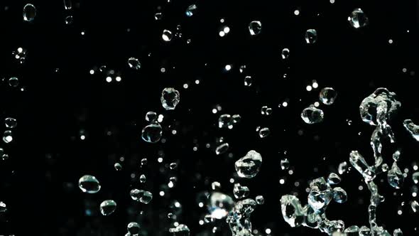 Water Droplets Rise in the Air Against Black Background. Slow Motion Water Splash on Black