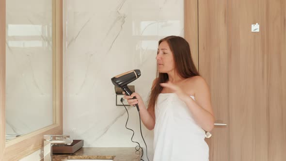 Delighted Young Woman Dances and Sings Into Hairdryer