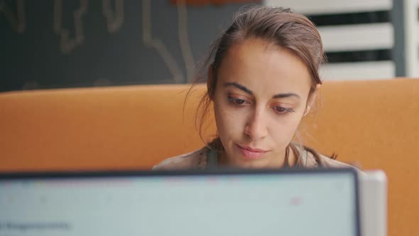 Pensive Woman Working at Laptop and Looking at Camera with Smile