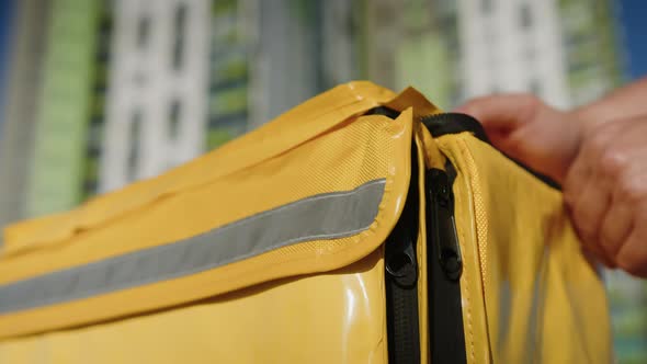 Hands of a Male Courier Who Closes a Yellow Thermo Bag After Delivering