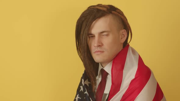 Young Man Wrapped in American Flag on Yellow Background