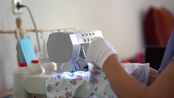 Female artisan on protective gloves sewing fabric masks