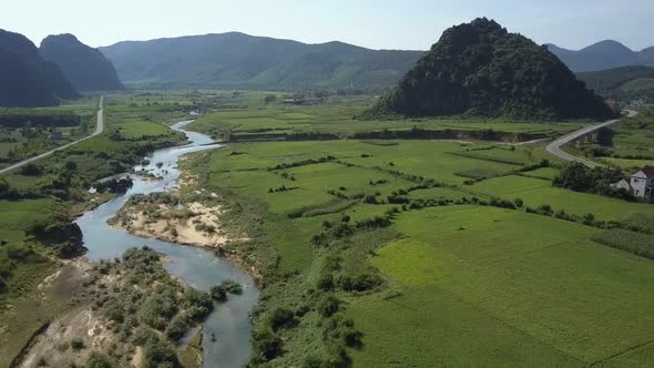 Aerial Motion Over Wide Field with Winding River and Roads