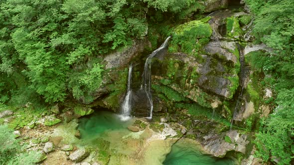 Aerial view of a waterfall surrounded by rocks and nature nearby Soca River.