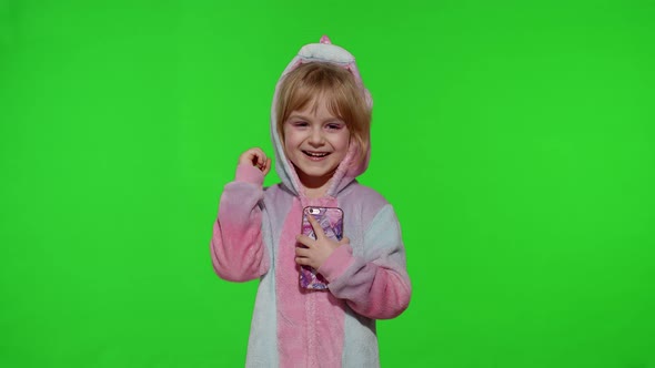 Excited Little Child Girl in Unicorn Pajamas Using Mobile Cell Phone Found Out Great Big Win News