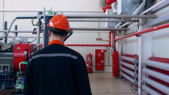 Follow the Footage of a Factory Worker in a Hard Hat Walking Through Industrial Facilities