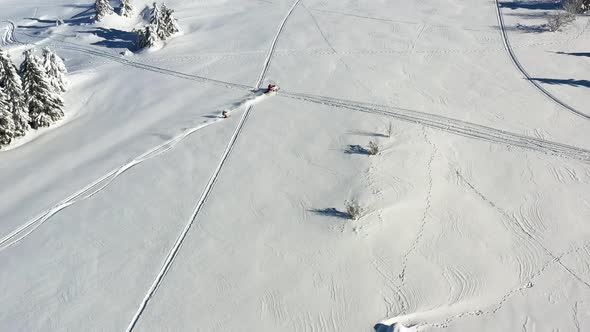 Aerial View of Snowmobile Towing Skier on Snow Capped Mountain on a Sunny Winter Day, Tracking Drone