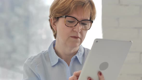 Old Woman Using Tablet for Browsing Internet