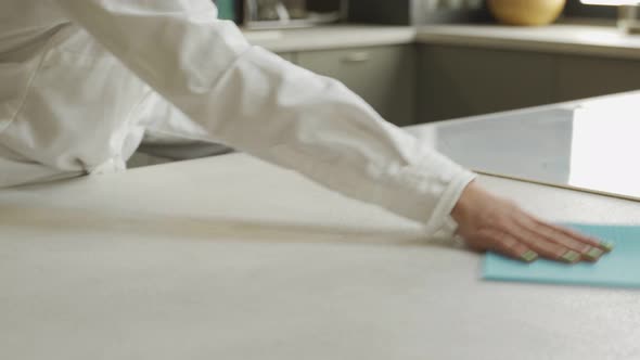 Young Woman Cleans Table with Cloth in Kitchen at Home