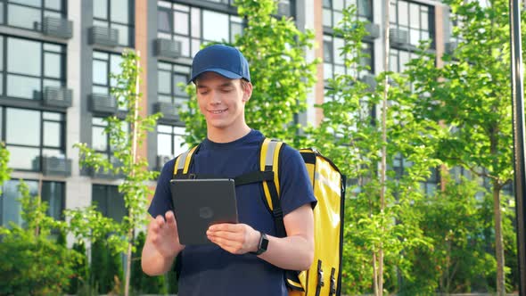 Portrait Smiling Man Courier Food Delivery with Thermal Backpack Uses Tablet