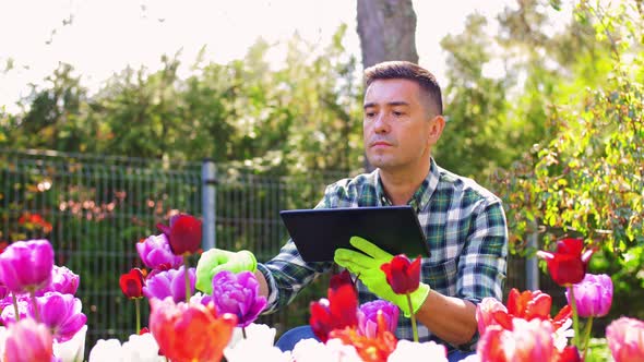 Man with Tablet Pc and Flowers at Summer Garden