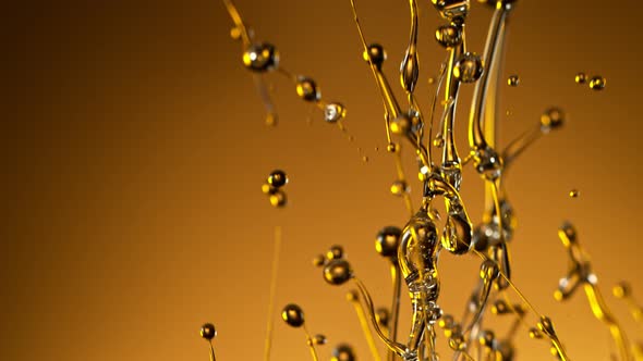 Super Slow Motion Shot of Splashing Oil on Golden Background at 1000Fps