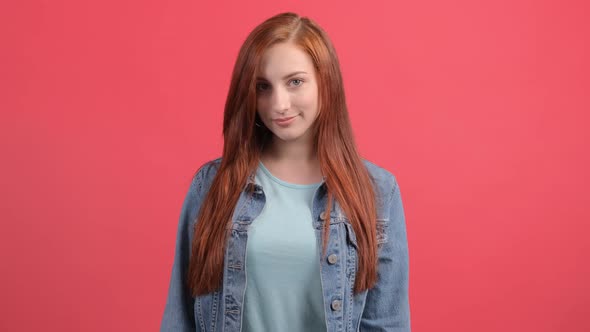 Happy Young Woman Showing Ok Sign with Fingers and Winking Isolated on a Red Background.