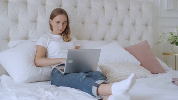 Smiling Woman Using Laptop Computer in the Bed, Everyday Use of Technology Concept