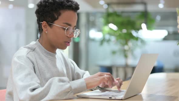 Casual African Woman with Laptop Smiling at the Camera