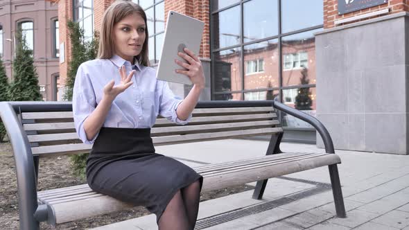 Online Video Chat on Tablet by Woman Sitting Outside Office