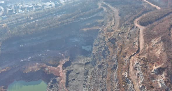 Misty Landscape Open Pit Stone Extraction in the Canyon with Deep Green Lake with Mountain Peaks in