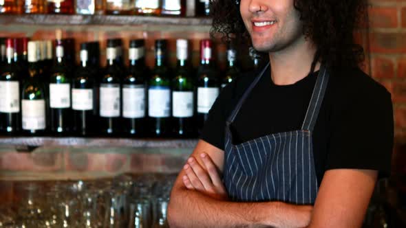 Portrait of barman standing with arms crossed at bar counter